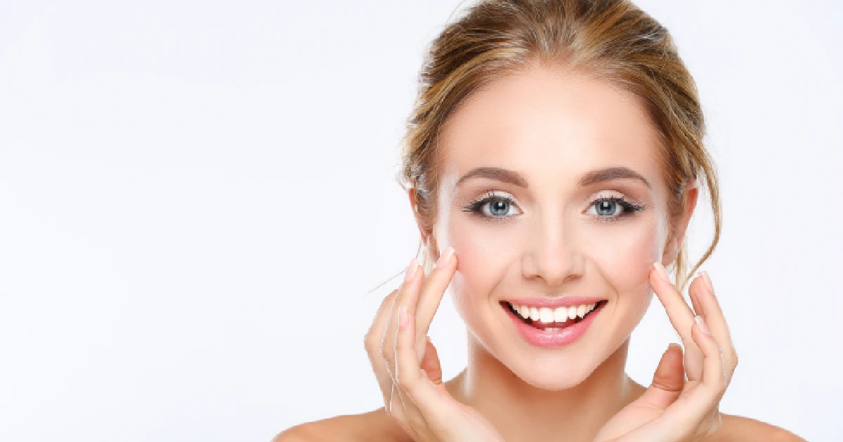 A smiling woman with glowing, healthy skin touching her result of BBL Heroic + SkinTyte